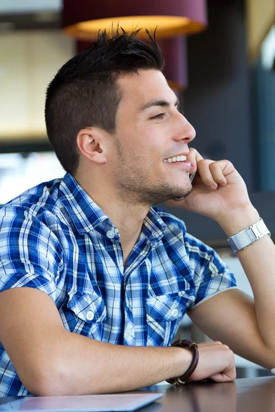 Молодой человек разговаривает по телефону в кафе — стоковое фото