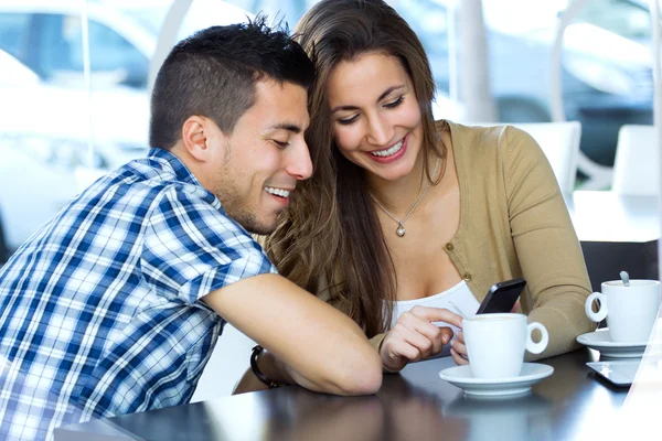 Молодая пара просматривает интернет со смартфоном в кафе — стоковое фото