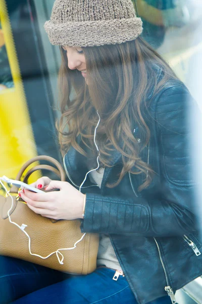 Jonge vrouw met haar mobiele telefoon tijdens het wachten voor de stadsbus — Stockfoto