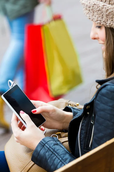 Junge Frau kauft mit Handy in der Stadt ein — Stockfoto