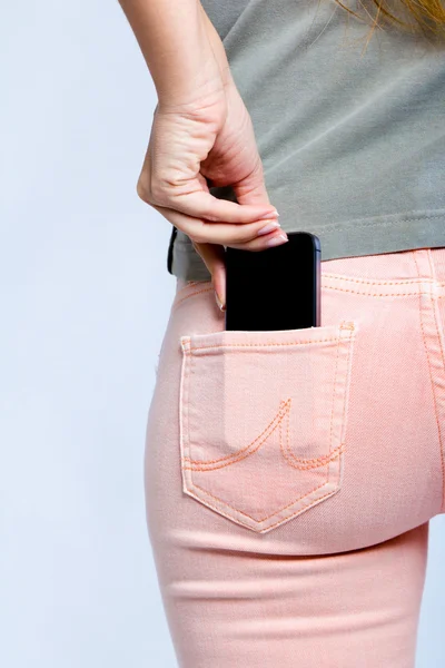 Черный смартфон в заднем кармане женских джинсов — стоковое фото