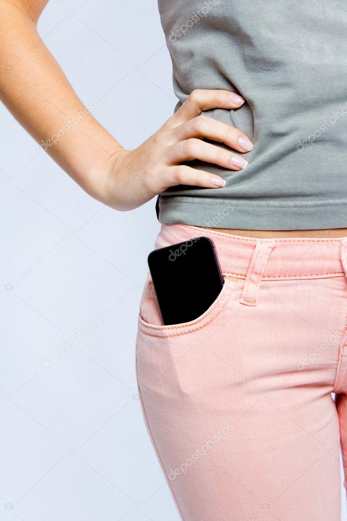 Black smartphone in front pocket of girl's jeans