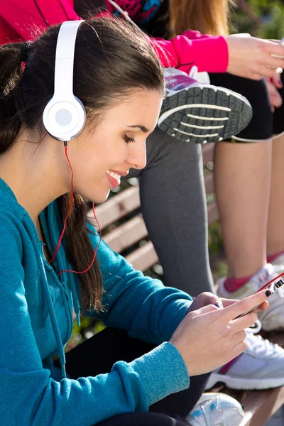 Linda chica escuchando música con smartphone después del ejercicio —  Fotos de Stock