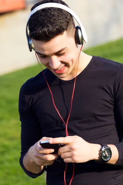 Мальчик слушает музыку со смартфоном на улице — стоковое фото