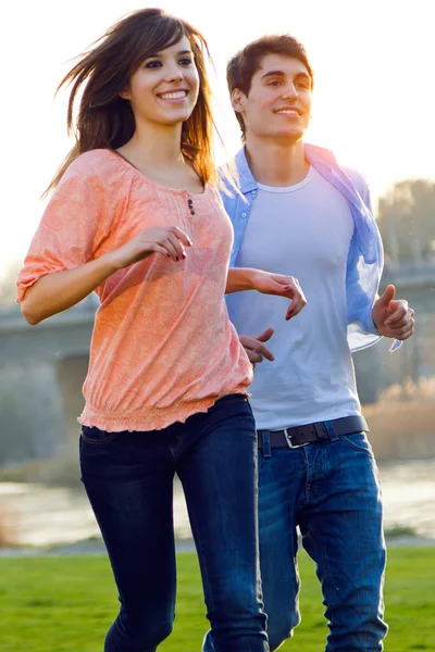 Счастливая молодая пара бегает вместе в парке — стоковое фото