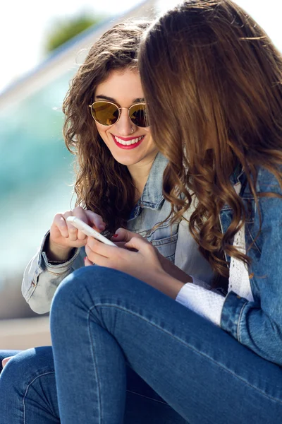 Две девушки развлекаются со смартфонами — стоковое фото