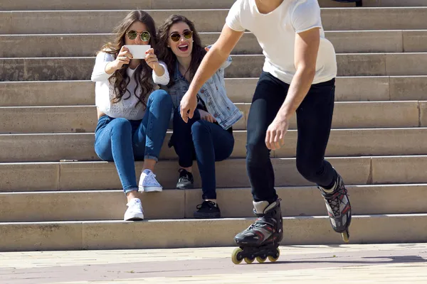 Roller skating boy with friends in town — Stock Photo, Image