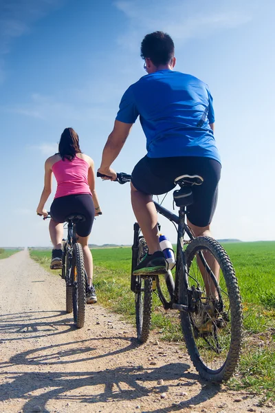 Gelukkige jonge paar op een fiets rijden op het platteland — Stockfoto