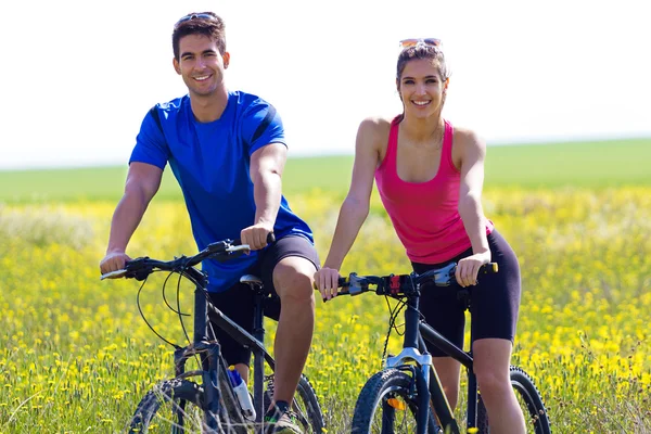 Gelukkige jonge paar op een fiets rijden op het platteland — Stockfoto