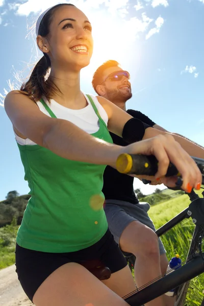 Feliz pareja joven en un paseo en bicicleta en el campo —  Fotos de Stock