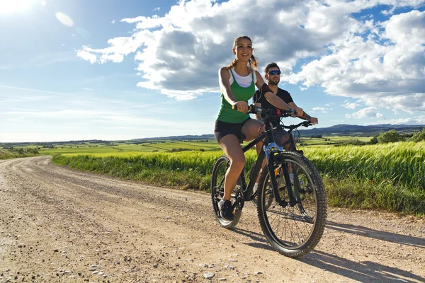 Felice giovane coppia in bicicletta in campagna — Foto Stock