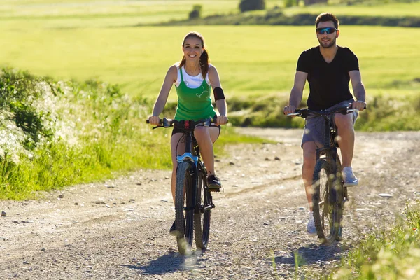 Šťastný mladý pár na kole jezdit na venkově — Stock fotografie