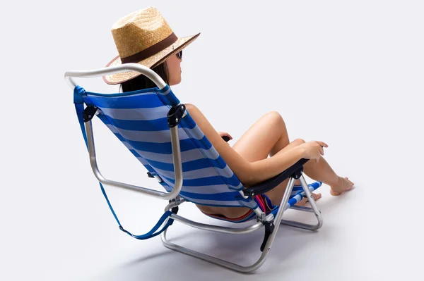 Mooie jonge vrouw met bikini zittend op een strandstoel — Stockfoto