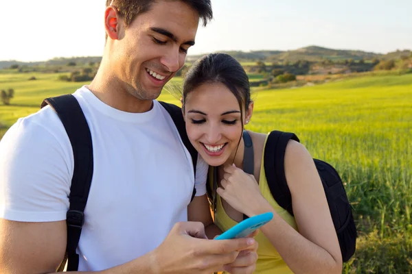 Giovane coppia all'aperto guardando il telefono cellulare — Foto Stock