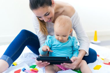 Dijital tablet kullanılarak evde anne ve bebek kız 