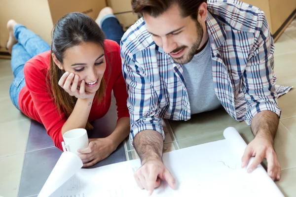 Pareja joven mirando los planos de su nuevo hogar — Foto de Stock