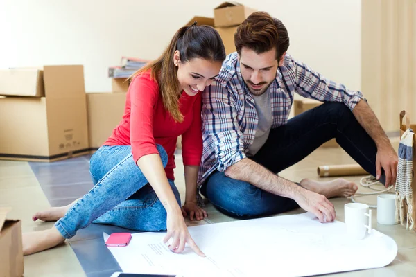 Young couple looking at the blueprints of their new home — Stock Photo, Image