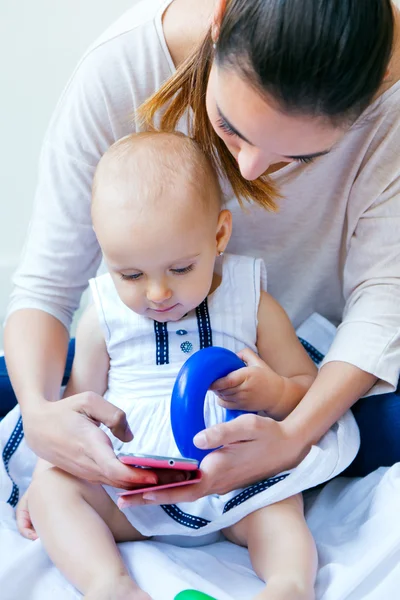 Mother and baby girl using a smartphone at home — Stock Photo, Image