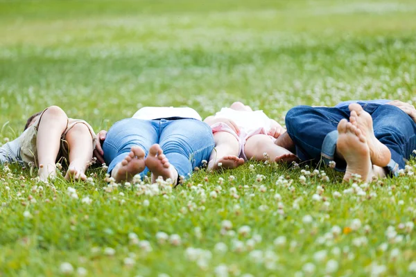 Gelukkige jonge familie liggen op grasszczęśliwe młode rodziny, leżąc na trawie — Zdjęcie stockowe