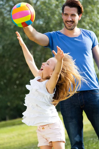 Feliz joven familia, padre e hijo jugando pelota en el parque . — Foto de Stock