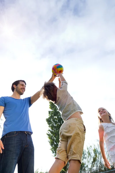 Feliz joven familia, padre e hijo jugando pelota en el parque . — Foto de Stock