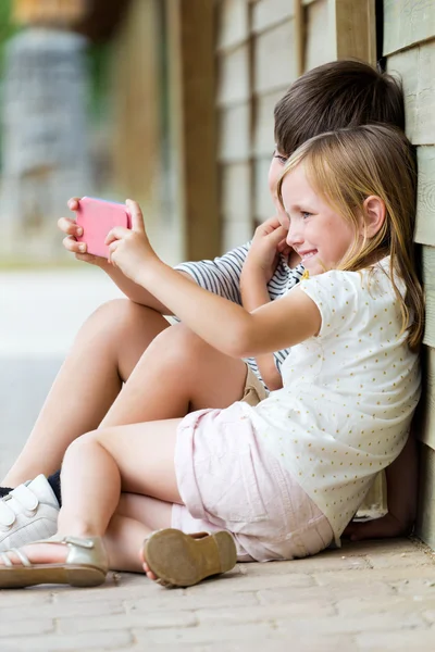 Felices hermanos jóvenes tomando selfies con su smartphone en la p — Foto de Stock