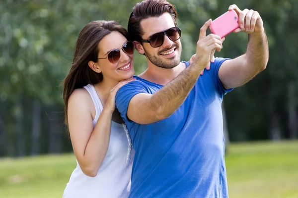 Happy young couple taking selfies with her smartphone in the par — Stock Photo, Image