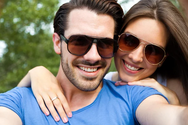 Feliz joven pareja tomando selfies con su smartphone a la par — Foto de Stock