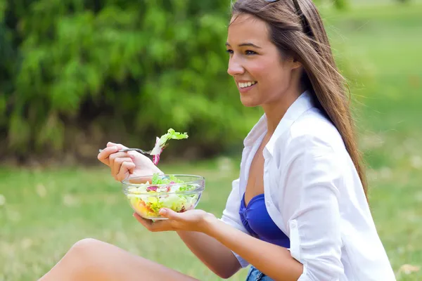 Beautiful young woman holding green salad, outdoors — Stock Photo, Image