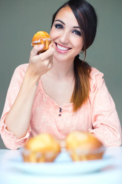 Jovem feliz mulher comendo deliciosos muffins — Fotografia de Stock