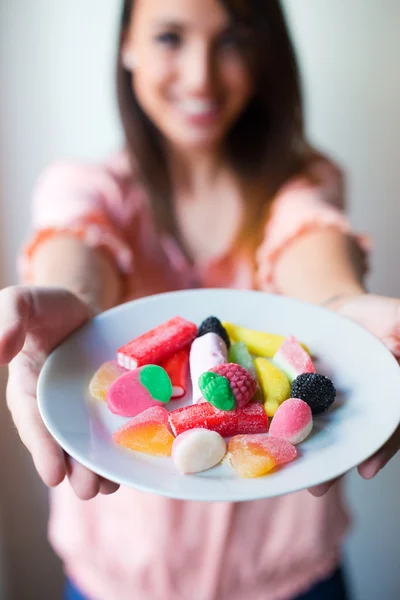 Süße junge Frau, die mit frischem Lächeln Gelee-Bonbons isst — Stockfoto