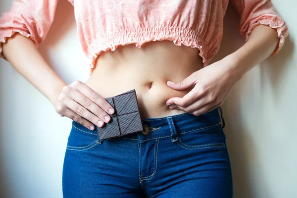 Молодая женщина с шоколадом показывает свой жир — стоковое фото