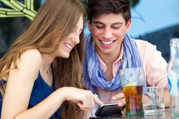 Pareja joven divirtiéndose con teléfonos inteligentes, al aire libre — Foto de Stock