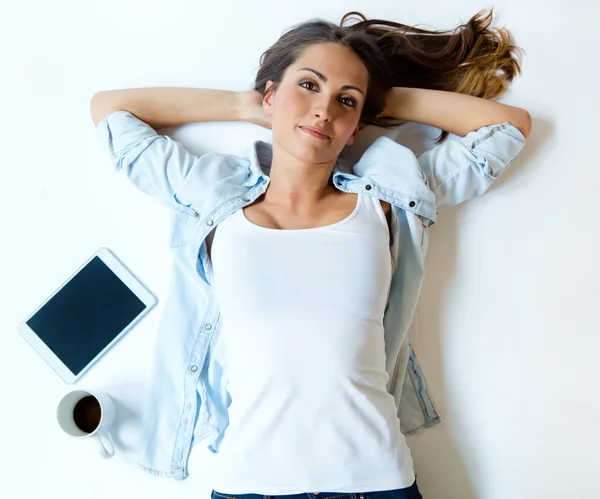 Overhead view of young woman lying on back on carpet alongside l — Stock Photo, Image