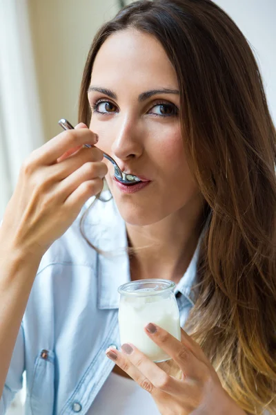 Giovane donna a casa mangiare yogurt — Foto Stock