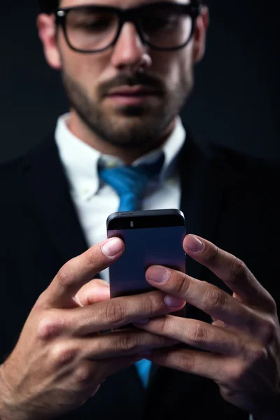 Knappe stijlvolle man in elegant zwart pak met behulp van mobiele telefoon. — Stockfoto