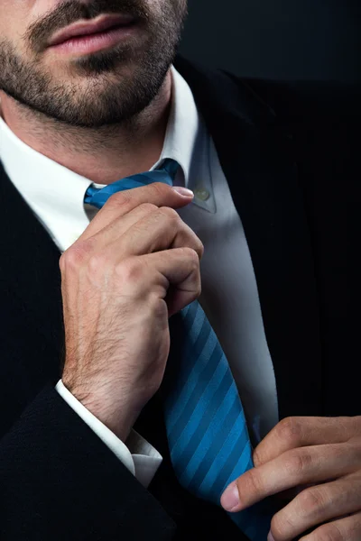 Businessman without face straightens tie himself. Isolated on black. — Stock Photo, Image