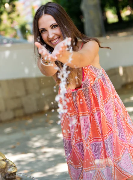 Schönes Mädchen spielt mit Wasser im Garten. — Stockfoto