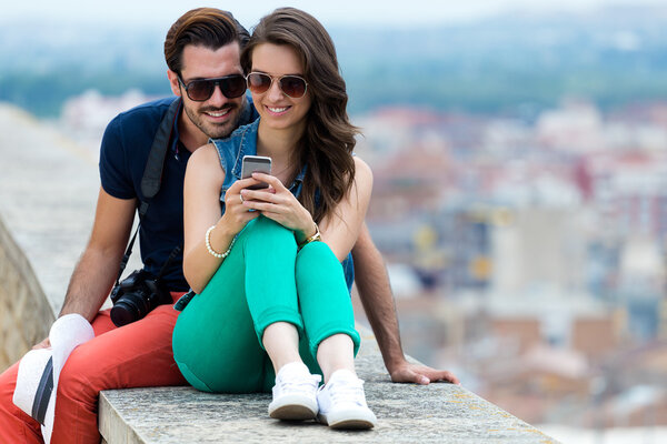 Young couple of tourist in town using mobile phone. 