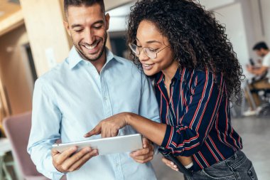 Bir iş yerinde birlikte tartışırken dijital tabletle çalışan iş adamlarının fotoğrafı.