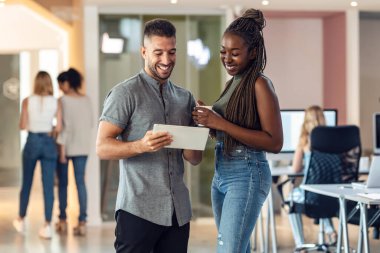 Bir iş yerinde birlikte tartışırken dijital tabletle çalışan iş adamlarının fotoğrafı.