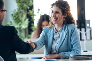 Güzel bir emlakçının elektronik tablette ev planlarını gösterirken olgun bir adamla gayrimenkul satın alma hakkında konuşurken çekilmesi.