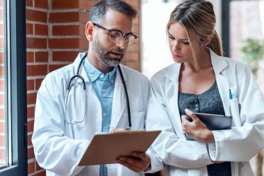 Tıbbi konsültasyonda kendine güvenen kadın ve erkek doktorların tıbbi bilgiler hakkında konuştuğu bir iğne..