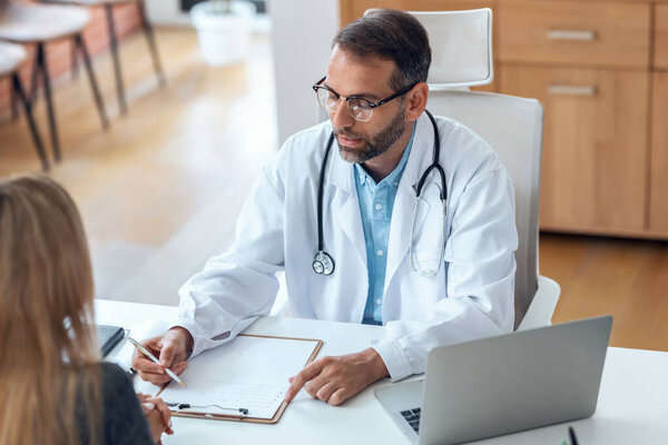 выстрел красивого взрослого врача мужского пола, говорящего во время объяснения лечения пациенту в консультации.