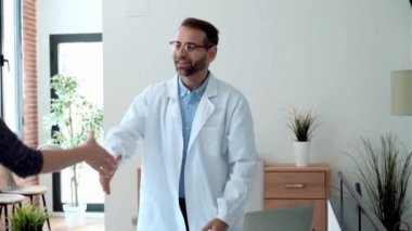 Yakışıklı, olgun bir erkek doktorun bir hastayla el sıkışırken çekilmiş bir video..
