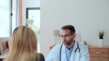 Yakışıklı, olgun bir doktorun hastaya muayenede tıbbi tedaviyi açıklarken konuştuğu video..