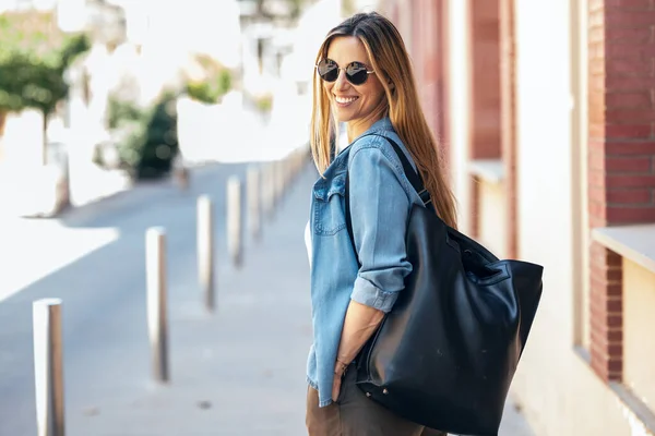 Shot of beautiful mature business woman looking at camera while walking down the street.