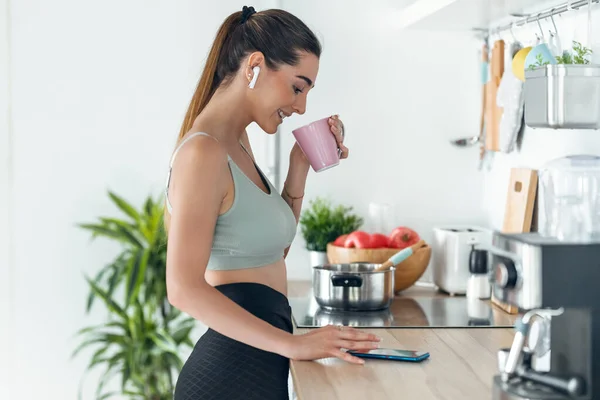 Evde Mutfakta Kahve Içerken Akıllı Telefonuyla Müzik Dinleyen Sportif Bir — Stok fotoğraf