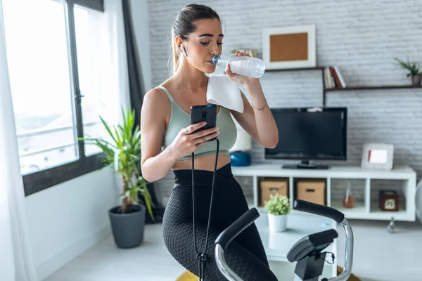 Skott Fitness Kvinna Som Använder Mobiltelefon Och Dricksvatten Medan Tränar — Stockfoto