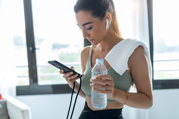 Tiro Mujer Fitness Usando Teléfono Móvil Agua Potable Mientras Entrena — Foto de Stock